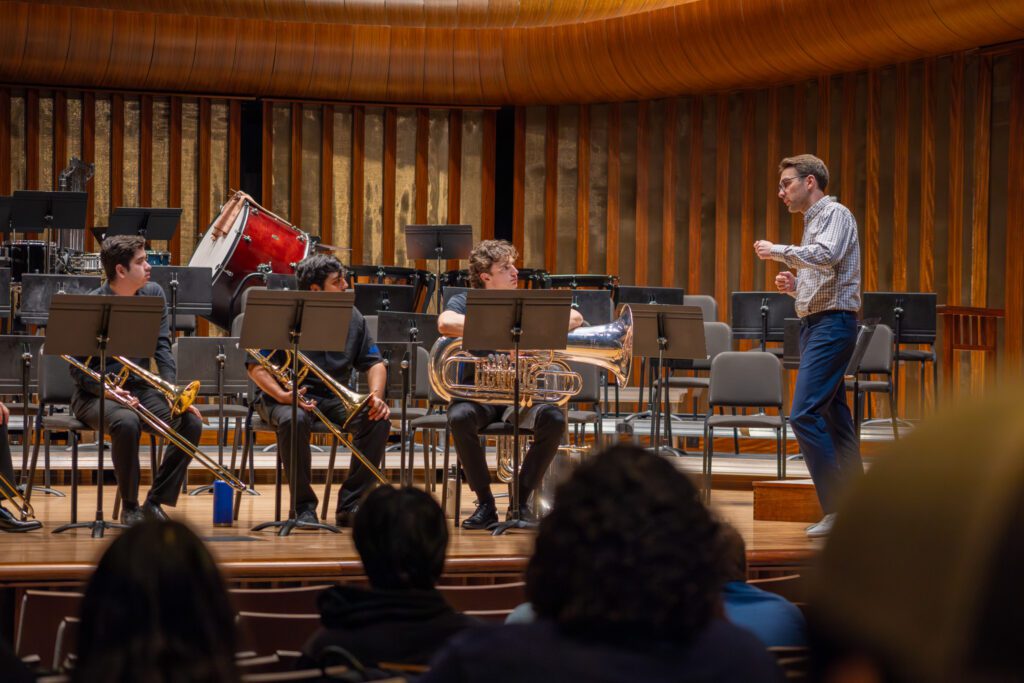 Principal Trombone Vladislav Petrachev instructs a group of student brass players on stage.